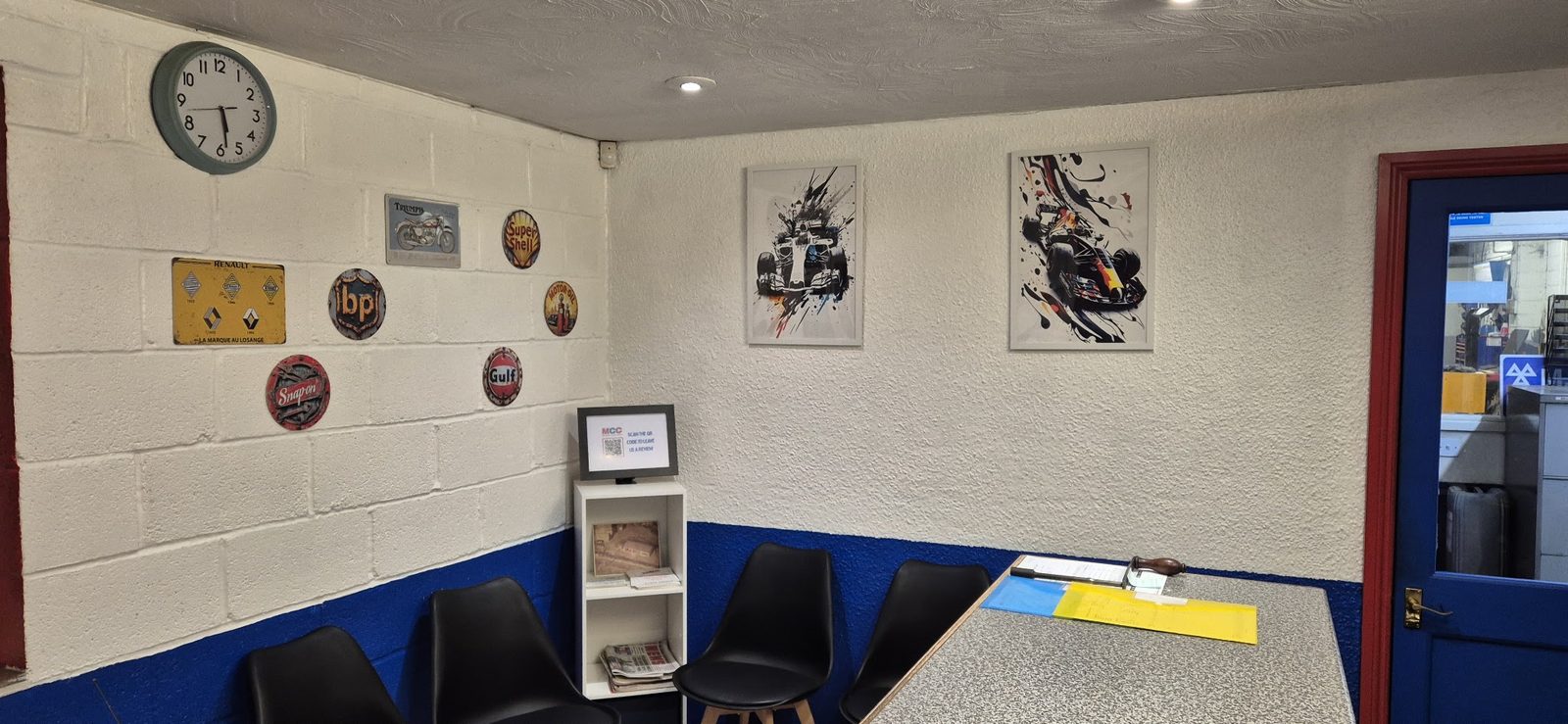 The waiting area with motorsport prints and enamel signs on the white block wall